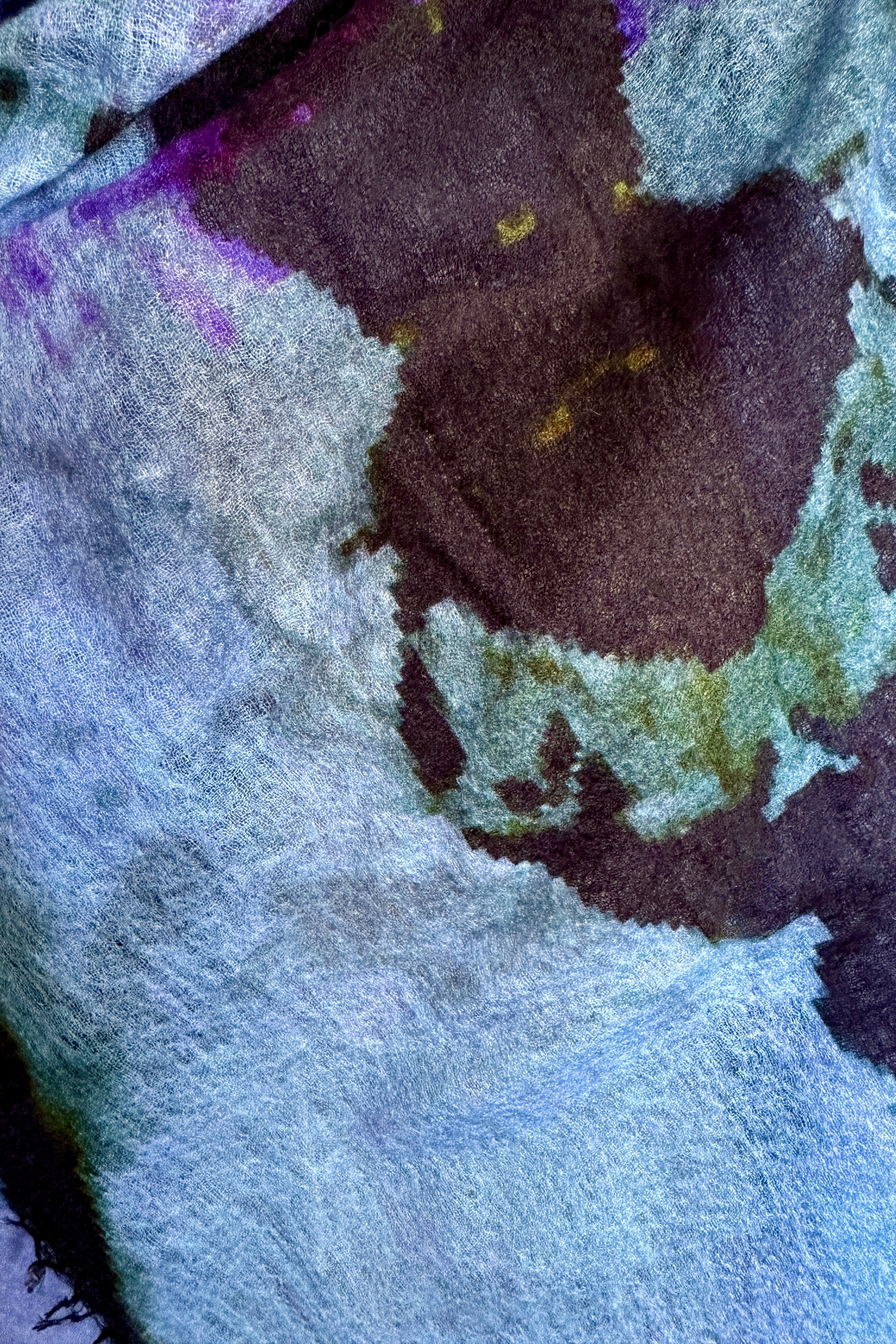 Close-up of a textured fabric with purple, green, and white colors.