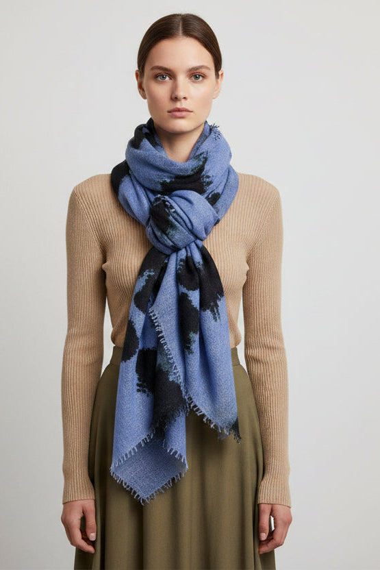 model wearing a blue scarf with black accents on a plain background