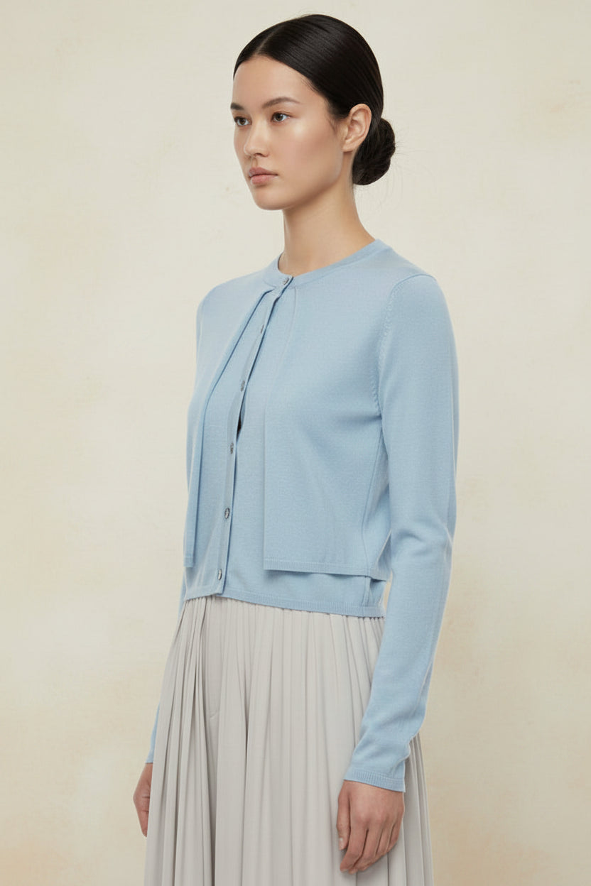 model wearing a light blue cardigan with black buttons against a plain background