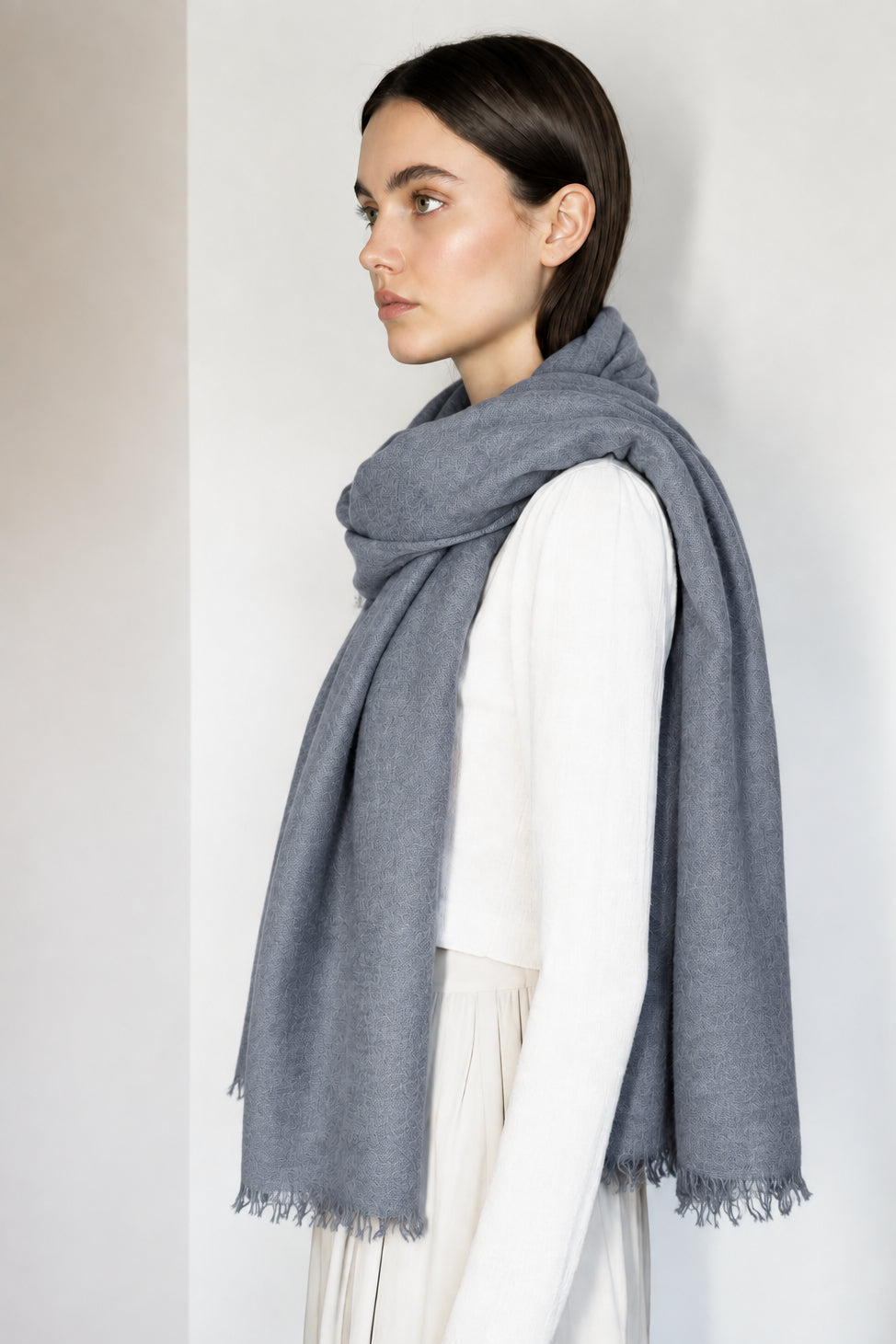 Woman wearing a gray scarf against a plain background