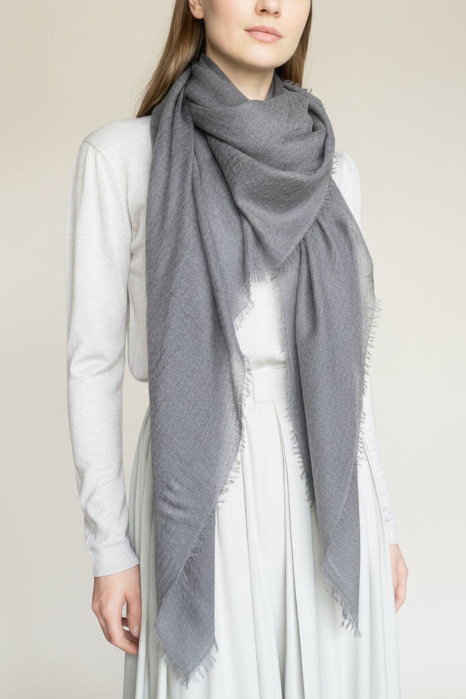 woman wearing a dark gra ycashmere scarf against a plain background
