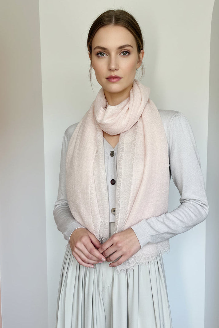 Mannequin wearing a light pink scarf and gray outfit against a plain background