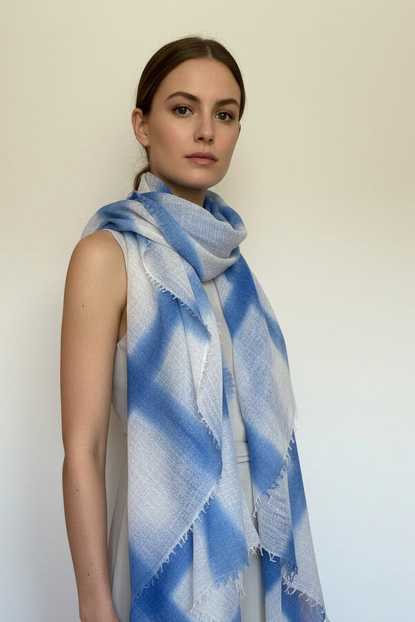 Mannequin wearing a blue and white patterned scarf in a room with wooden floor and white walls.