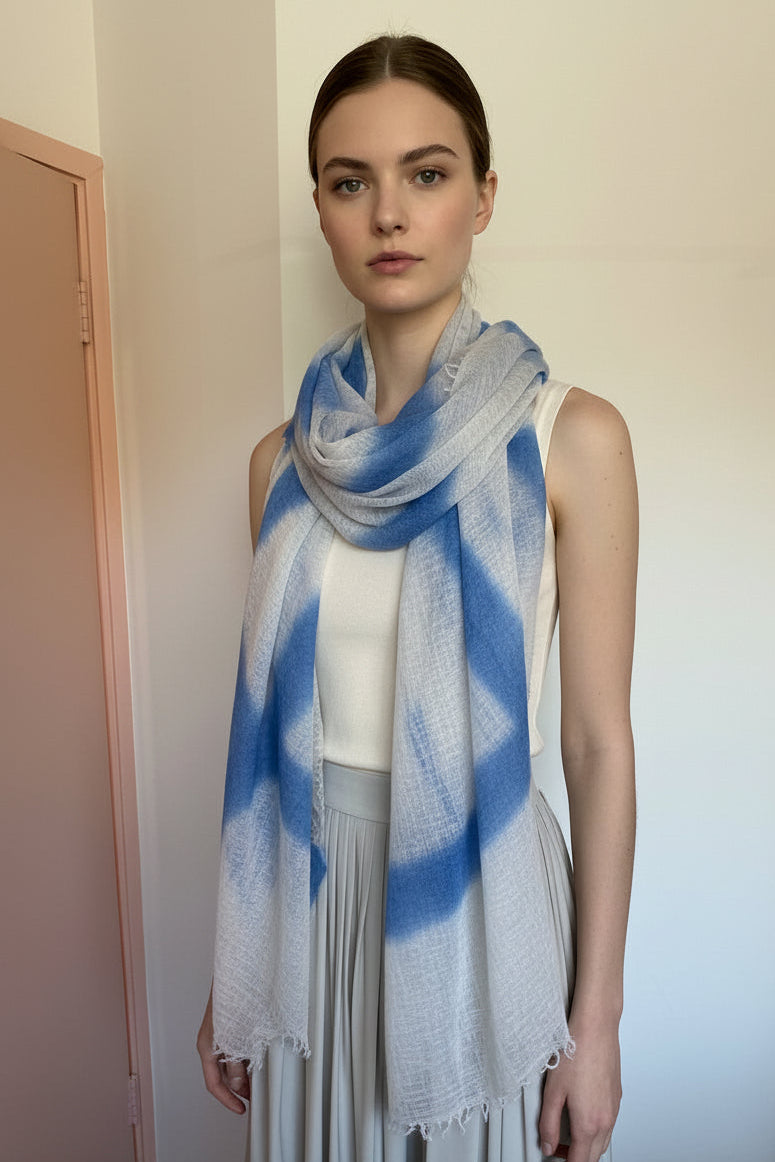 model wearing a blue and gray striped scarf in a room with a wooden floor.