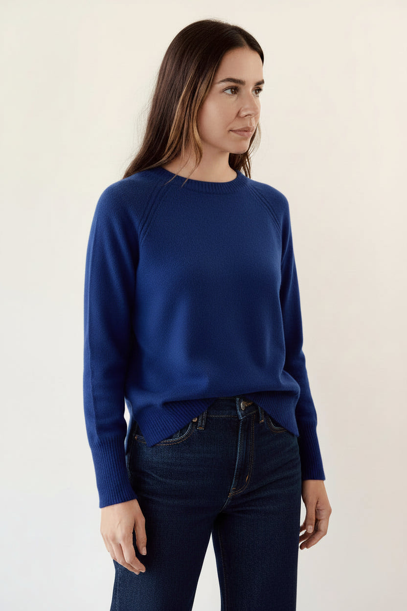 Person wearing a dark blue sweater against a plain background