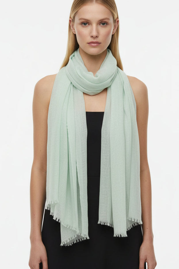 Model wearing a light green cashmere scarf on a white background