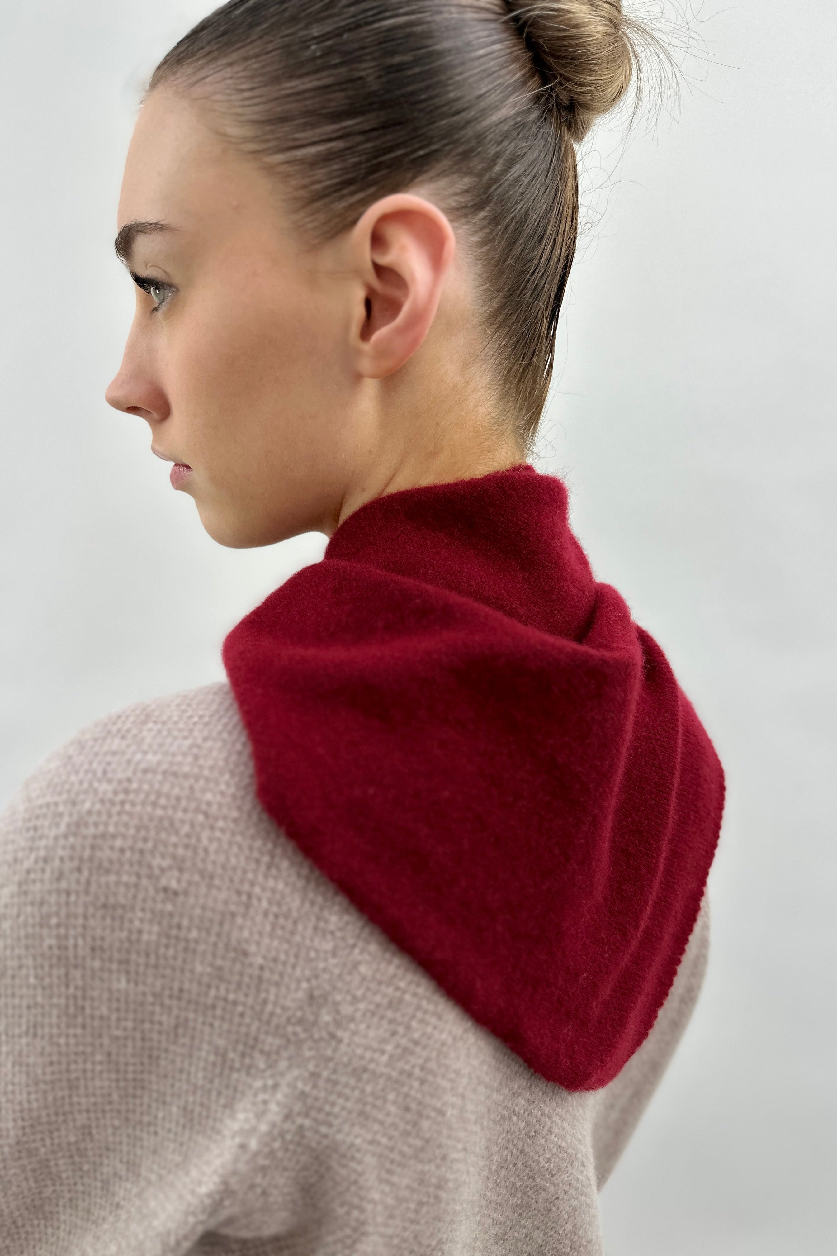 Person wearing a wine triangle scarf with a neutral background