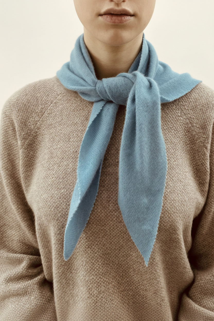Person wearing a light blue scarf around their neck with a neutral background