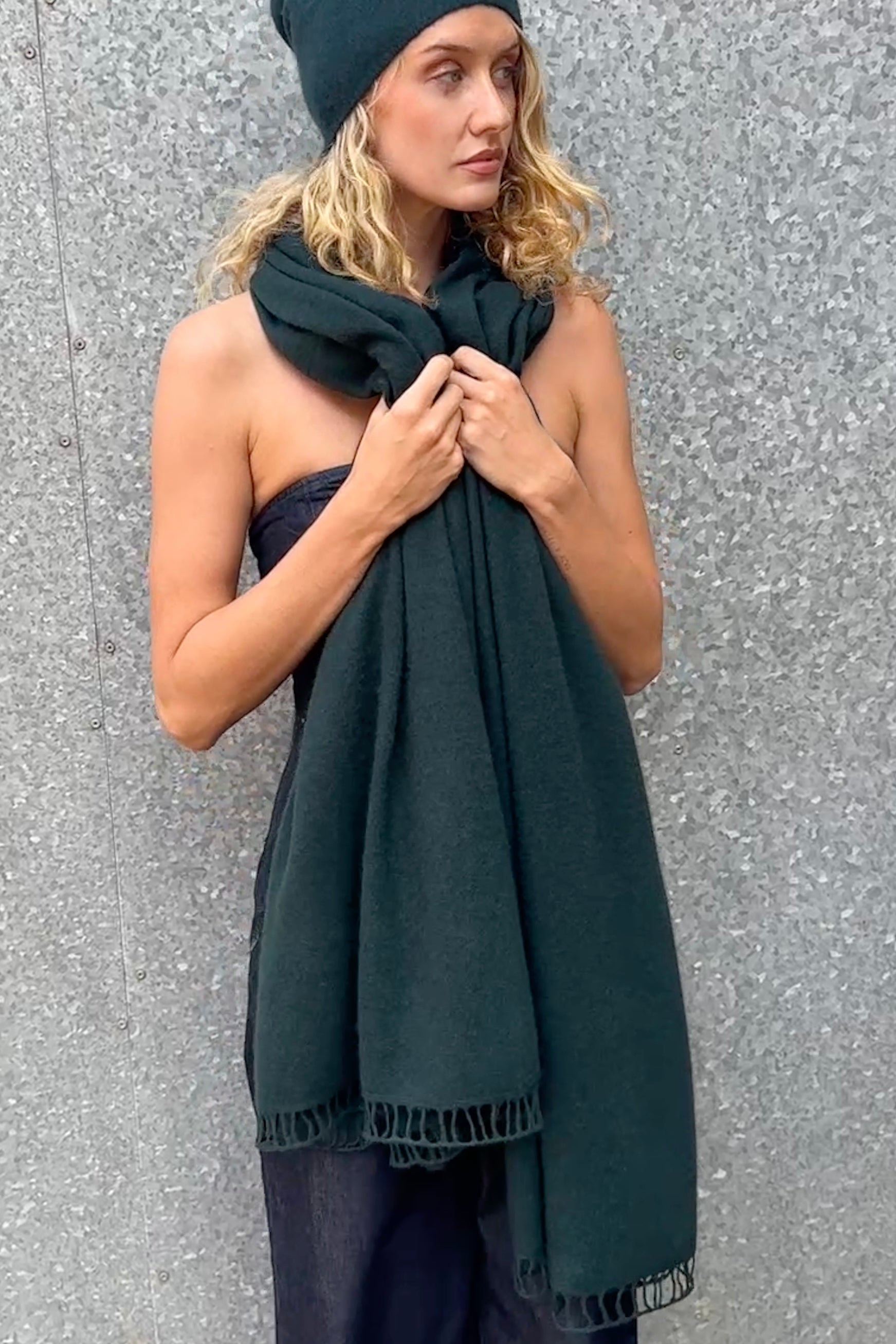 teal green cashmere scarf and hat on woman against a steel wall