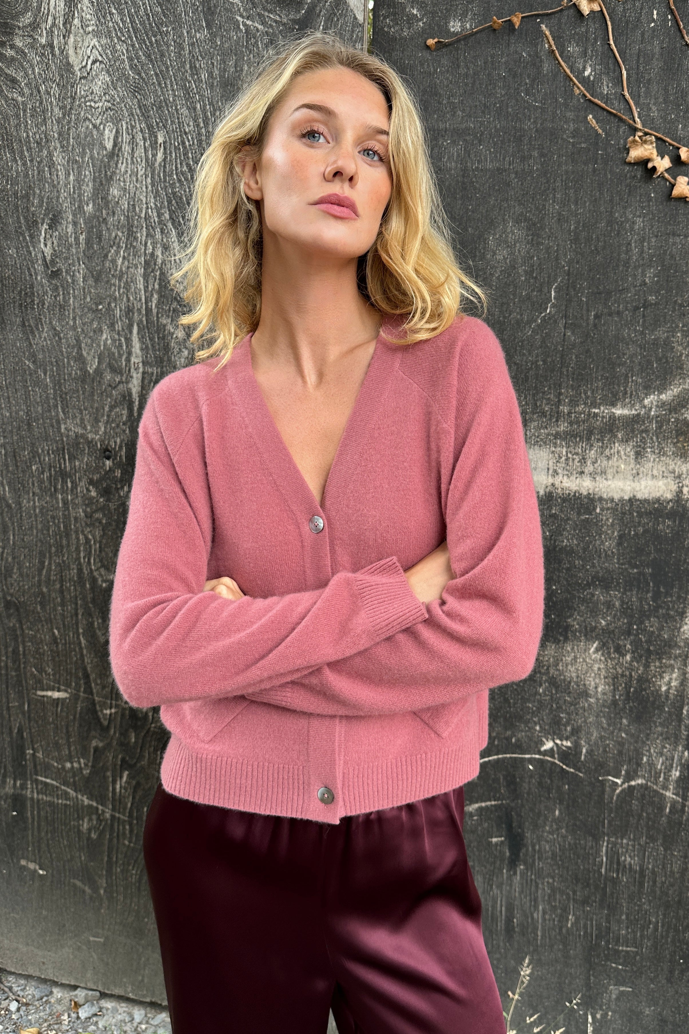 model wearing a zola rose pink cardigan against a textured dark background