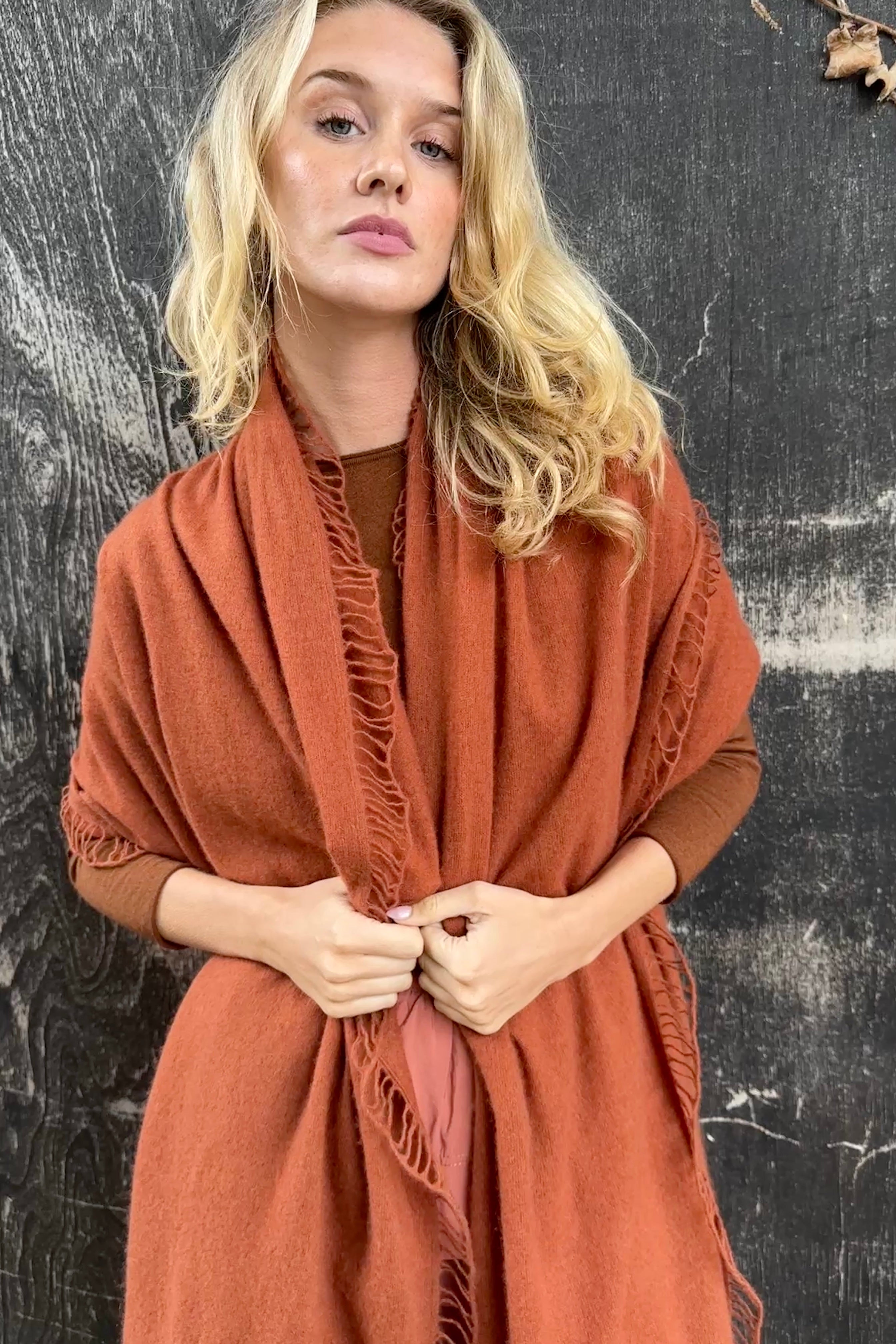 Woman wearing a rust-colored scarf against a textured black background