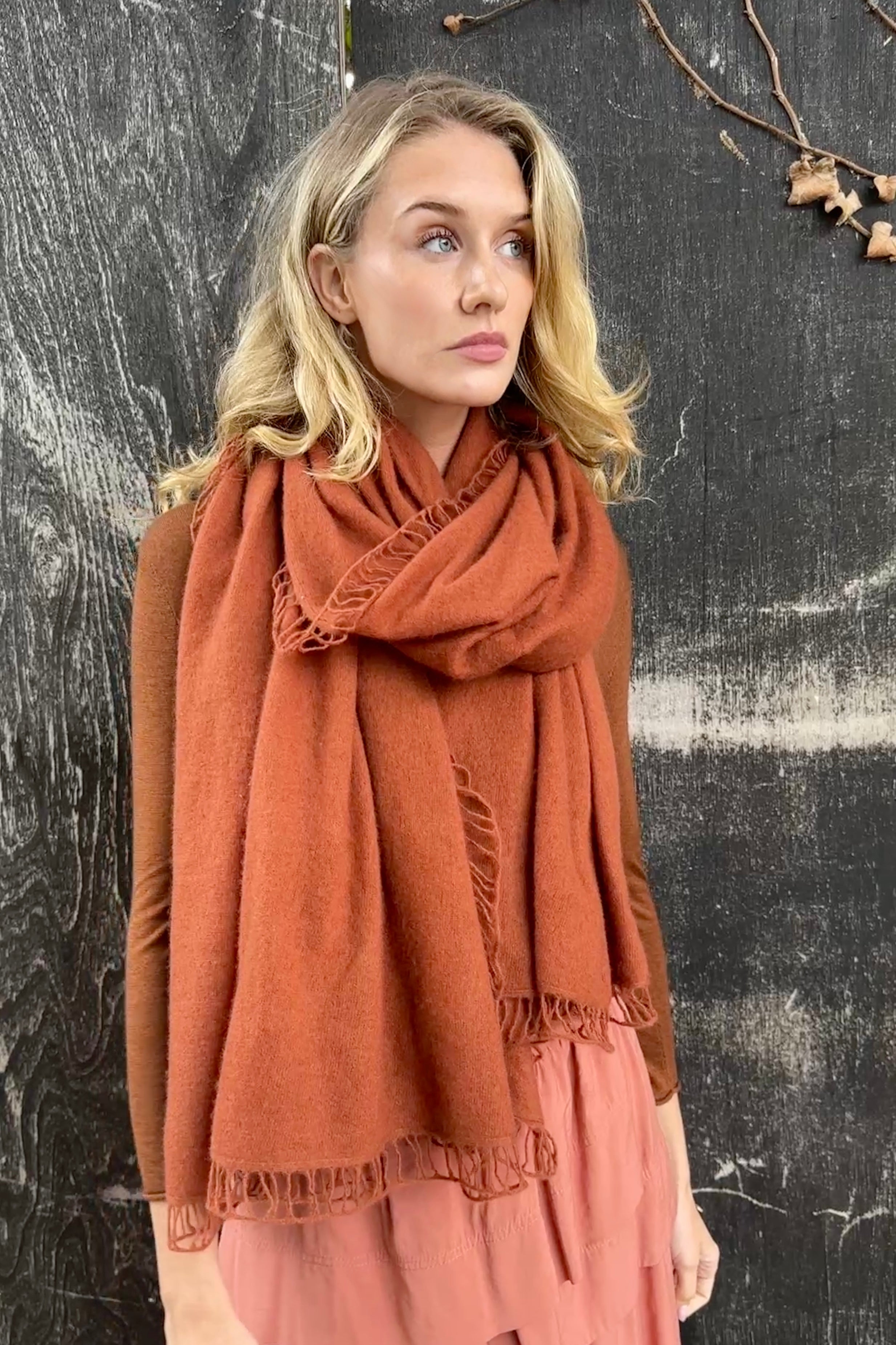 Woman wearing a rust-colored scarf against a textured black background