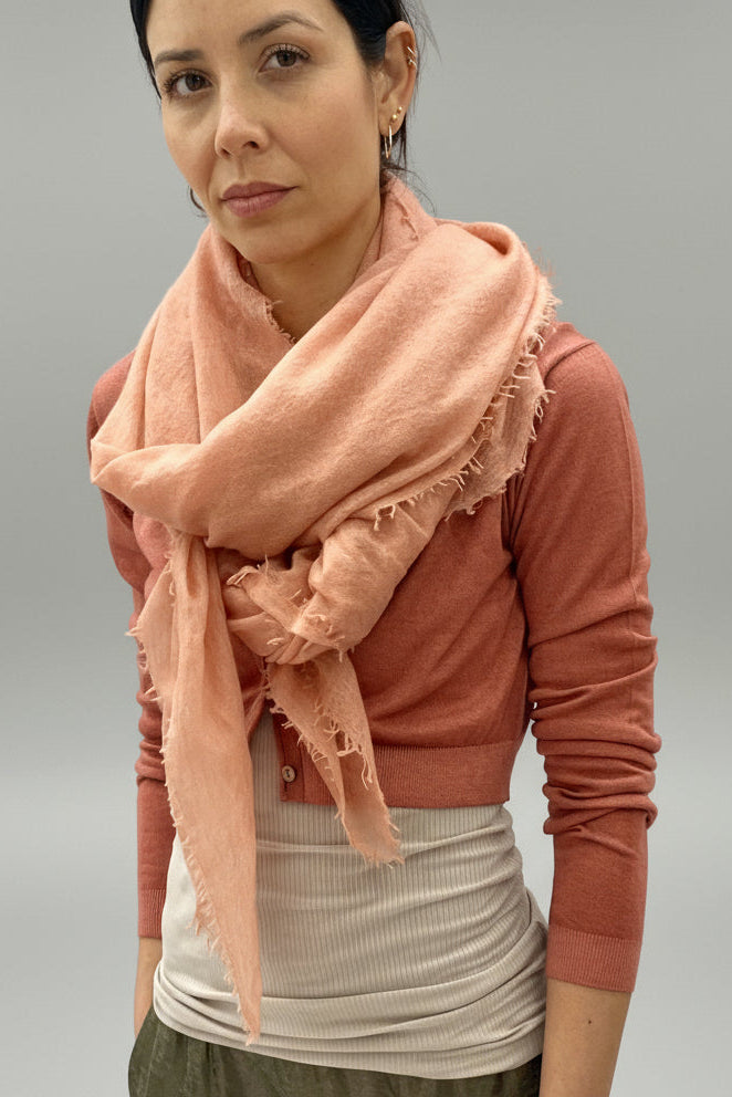 Woman wearing a pink scarf and brown top against a plain background