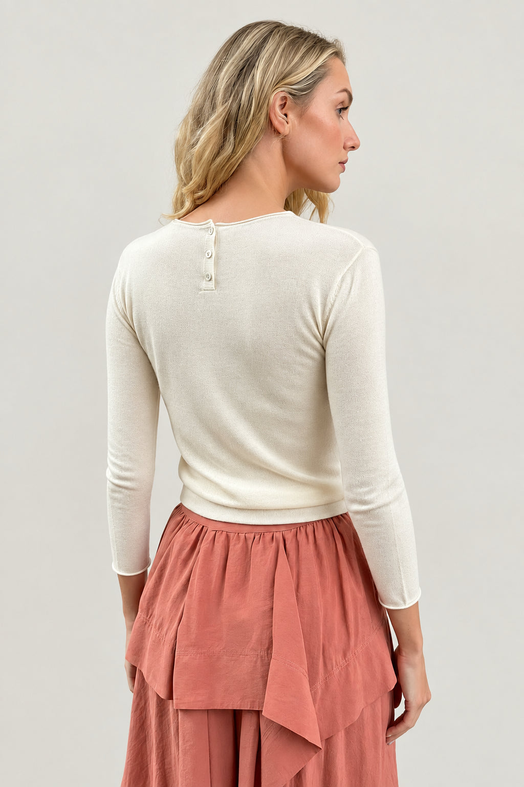 model wearing an ivory cashmere silk top or sweater and pink skirt back view