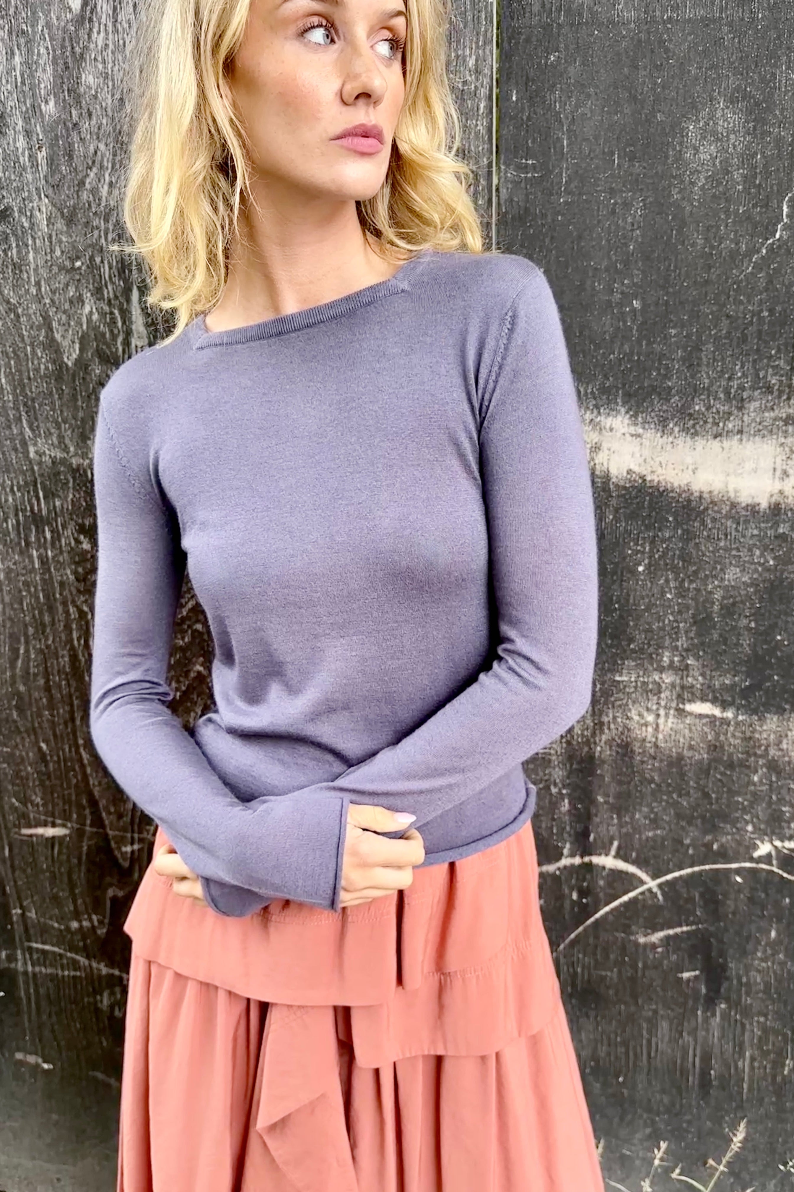 Model wearing a purple  lassa square neck long-sleeve top and pink skirt against a textured black background