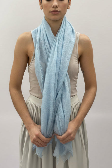 Woman holding a light blue scarf in front of a white background