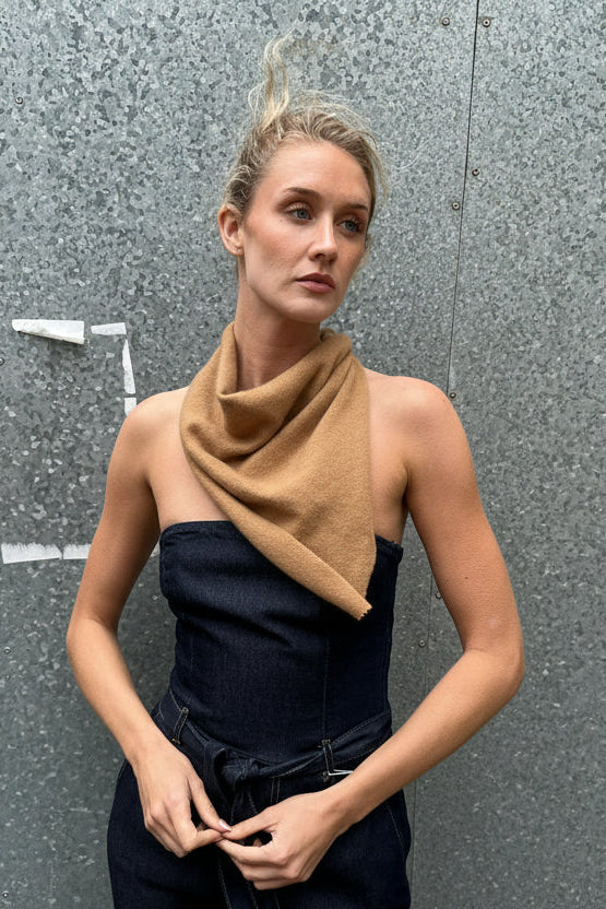 woman in a beige scarf against a grey wall