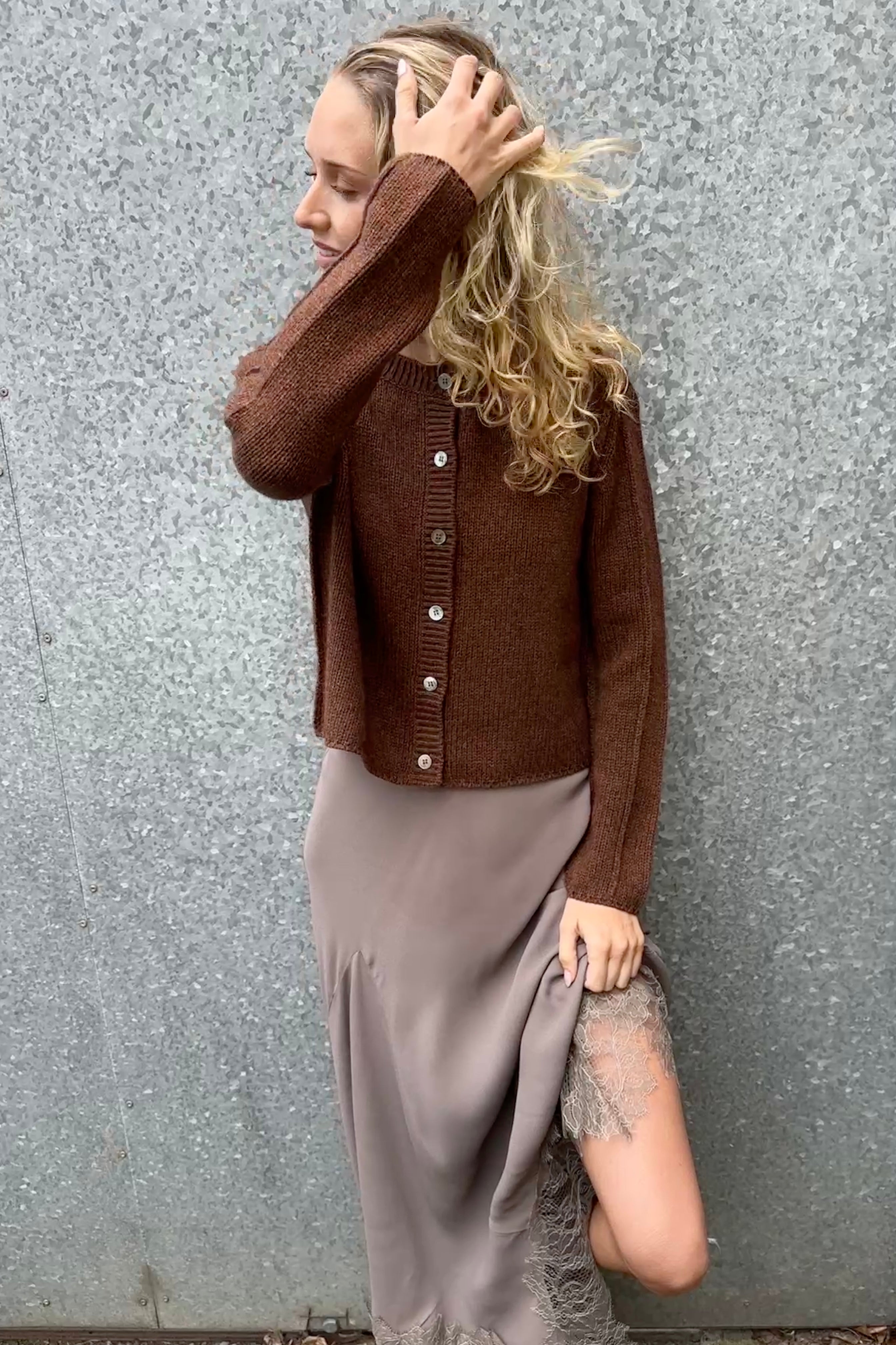 model wearing a brown cardigan against a gray wall