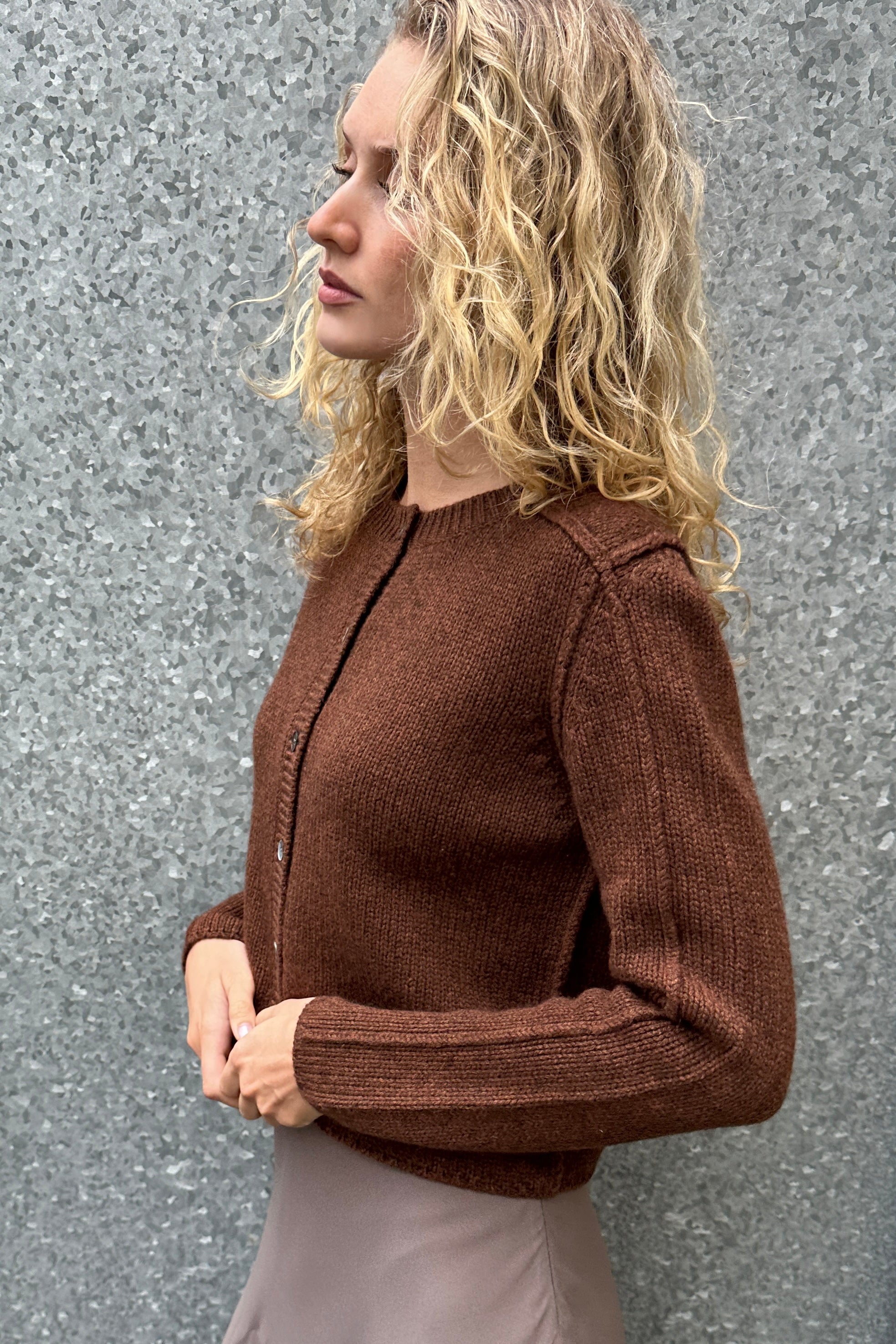 Woman wearing a brown sweater against a gray wall