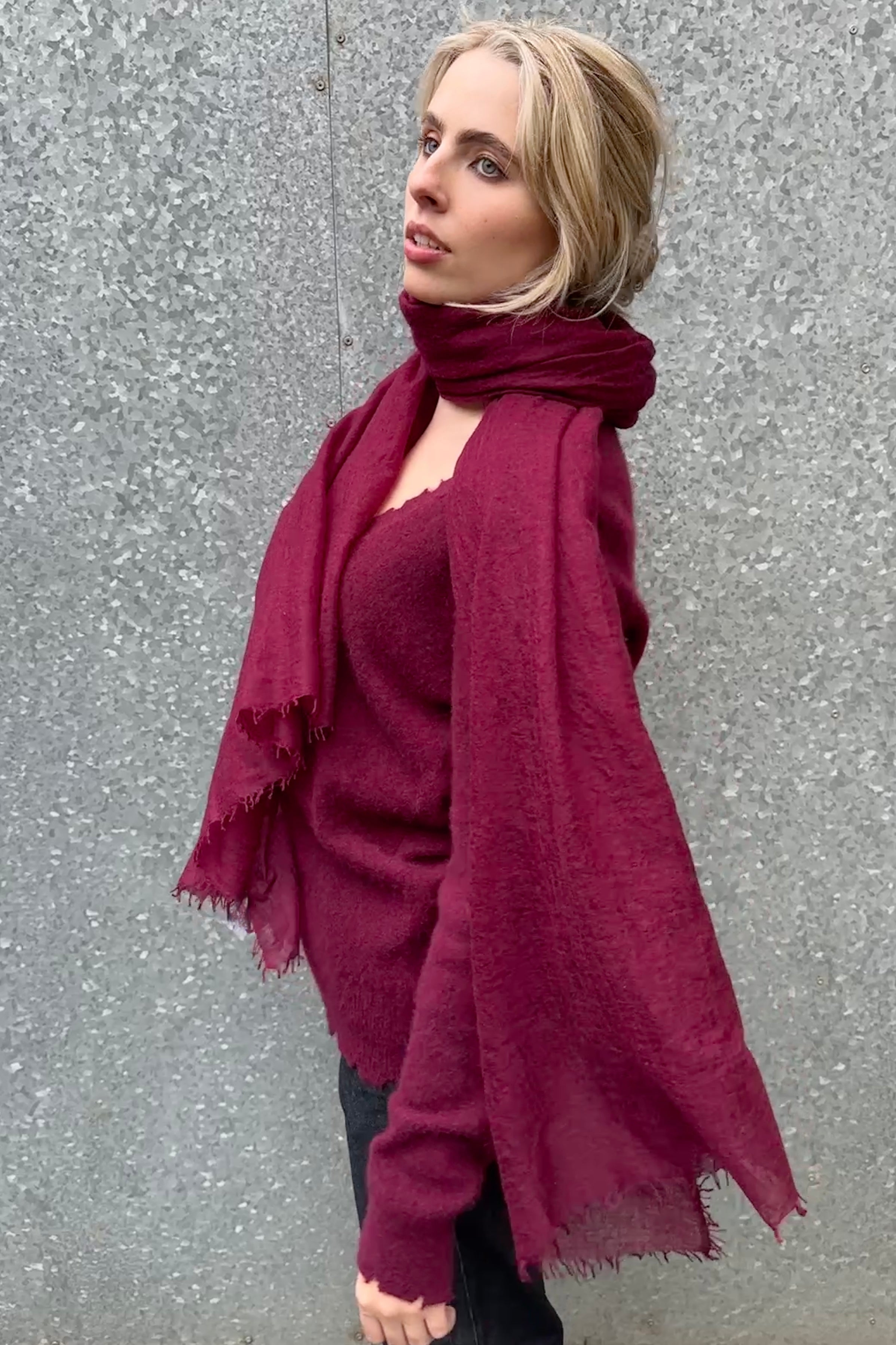 Woman wearing a burgundy scarf and sweater against a gray background