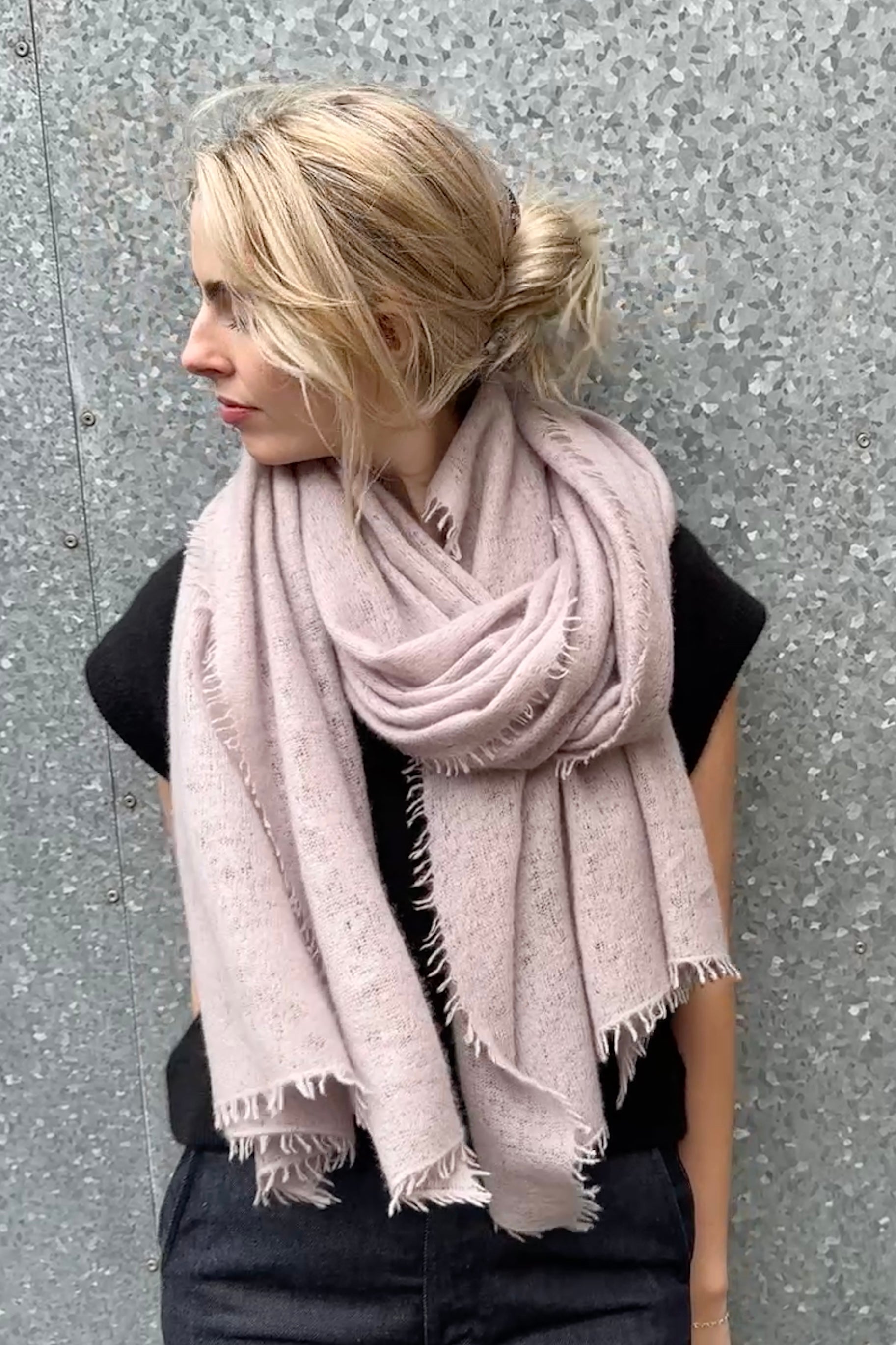Woman wearing a pink  grey cashmere scarf against a gray background