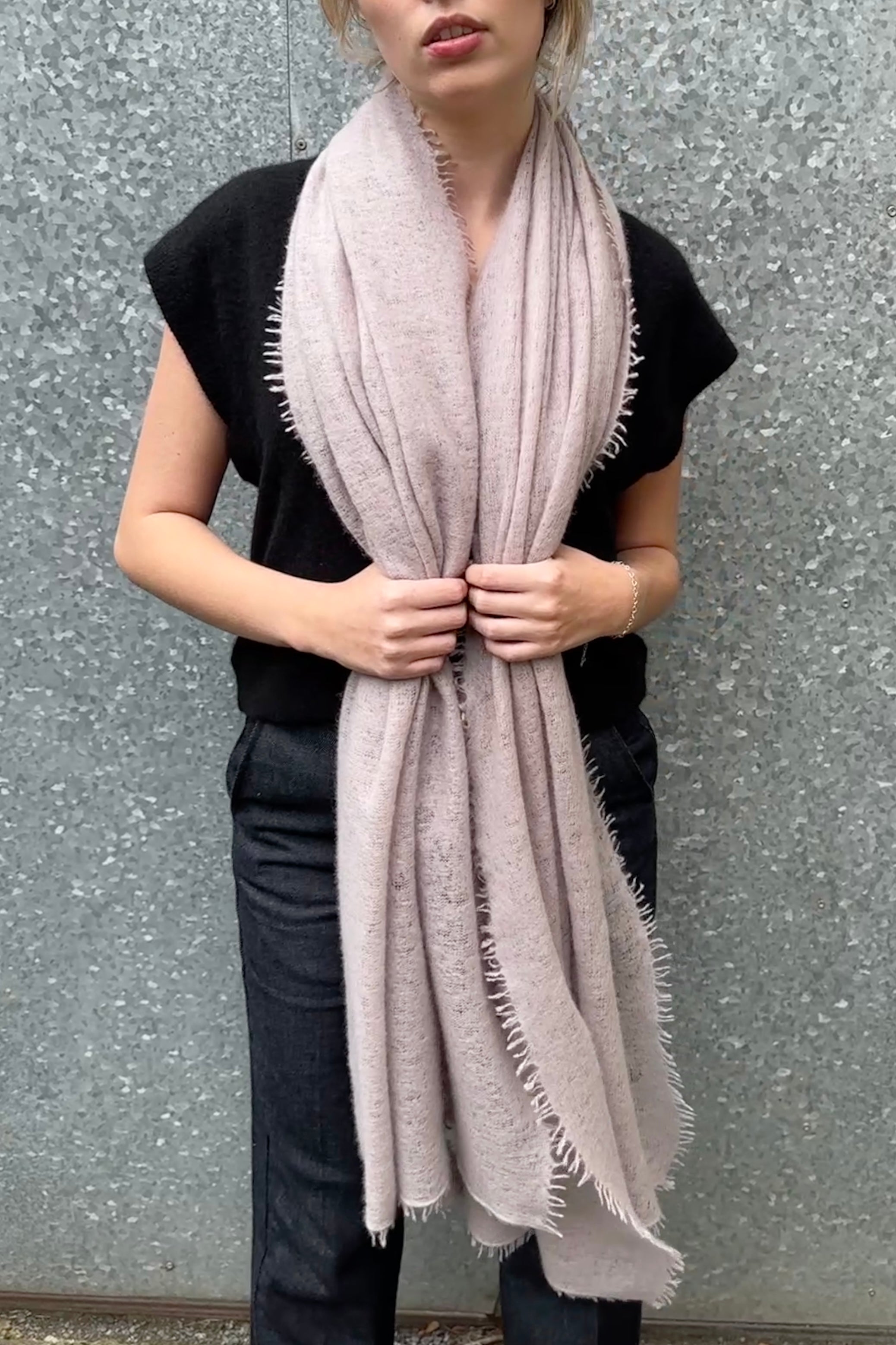 Person wearing a light pink scarf against a gray background