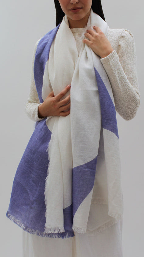 Woman wearing a white and purple scarf with a plain background