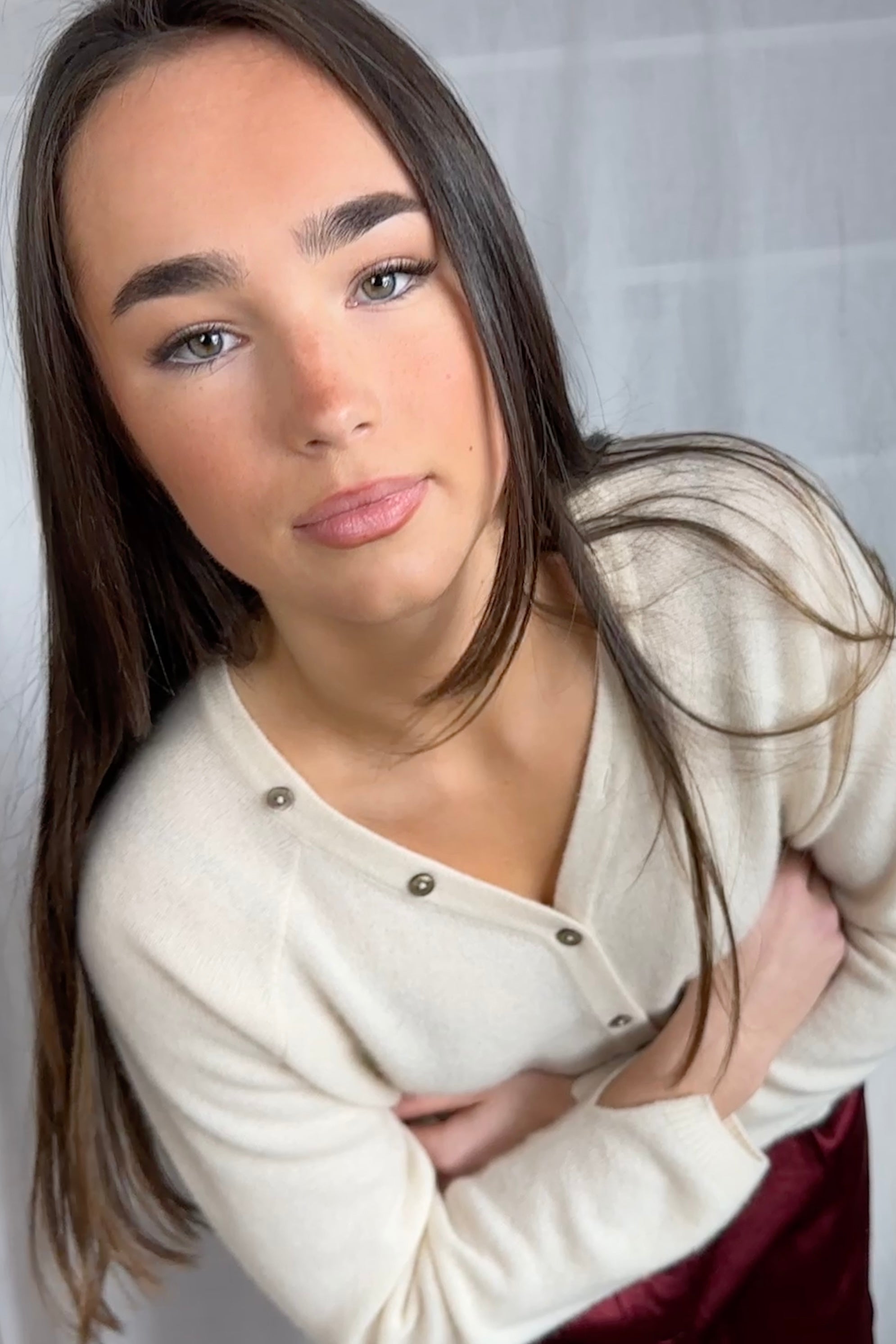 model wearing a cream cashmere cardigan against a plain background ,zelia feather close up