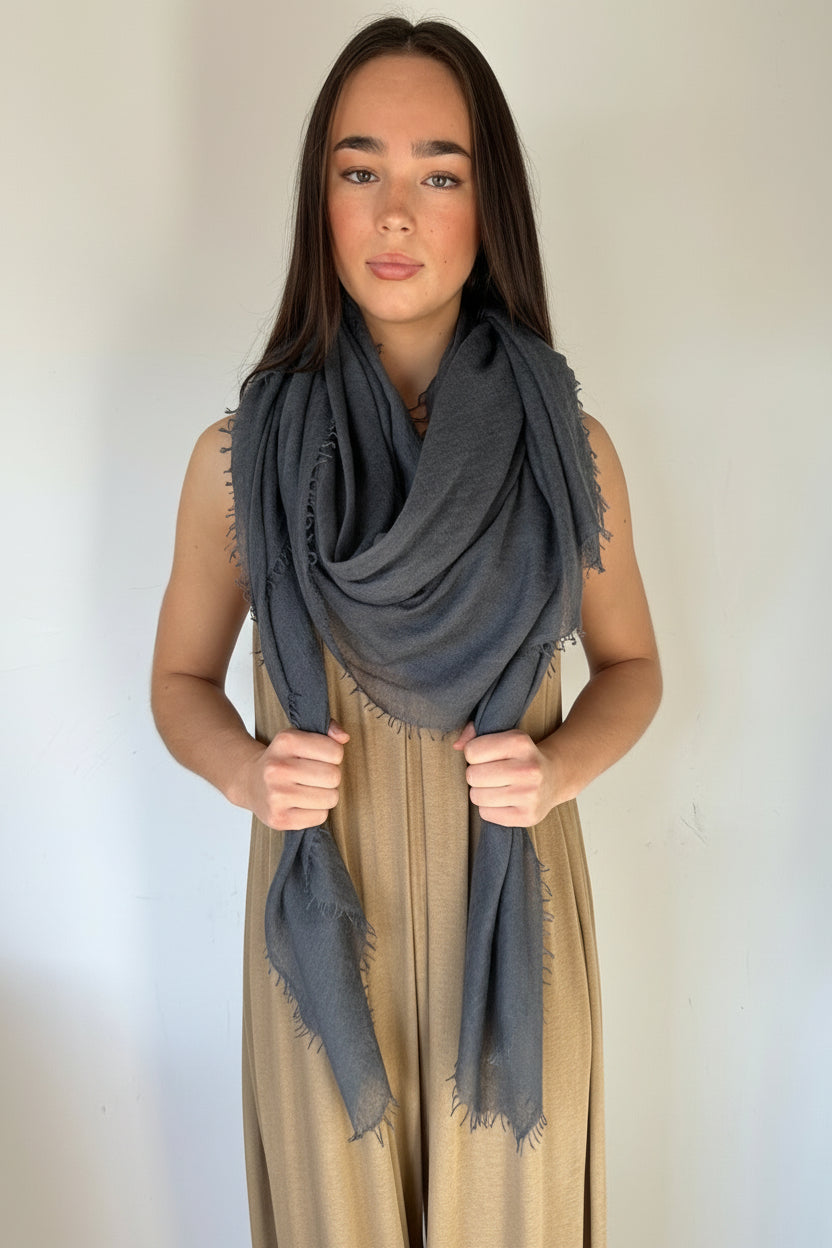Model wearing a large gray scarf petrol marmee cashmere around her neck against a plain background