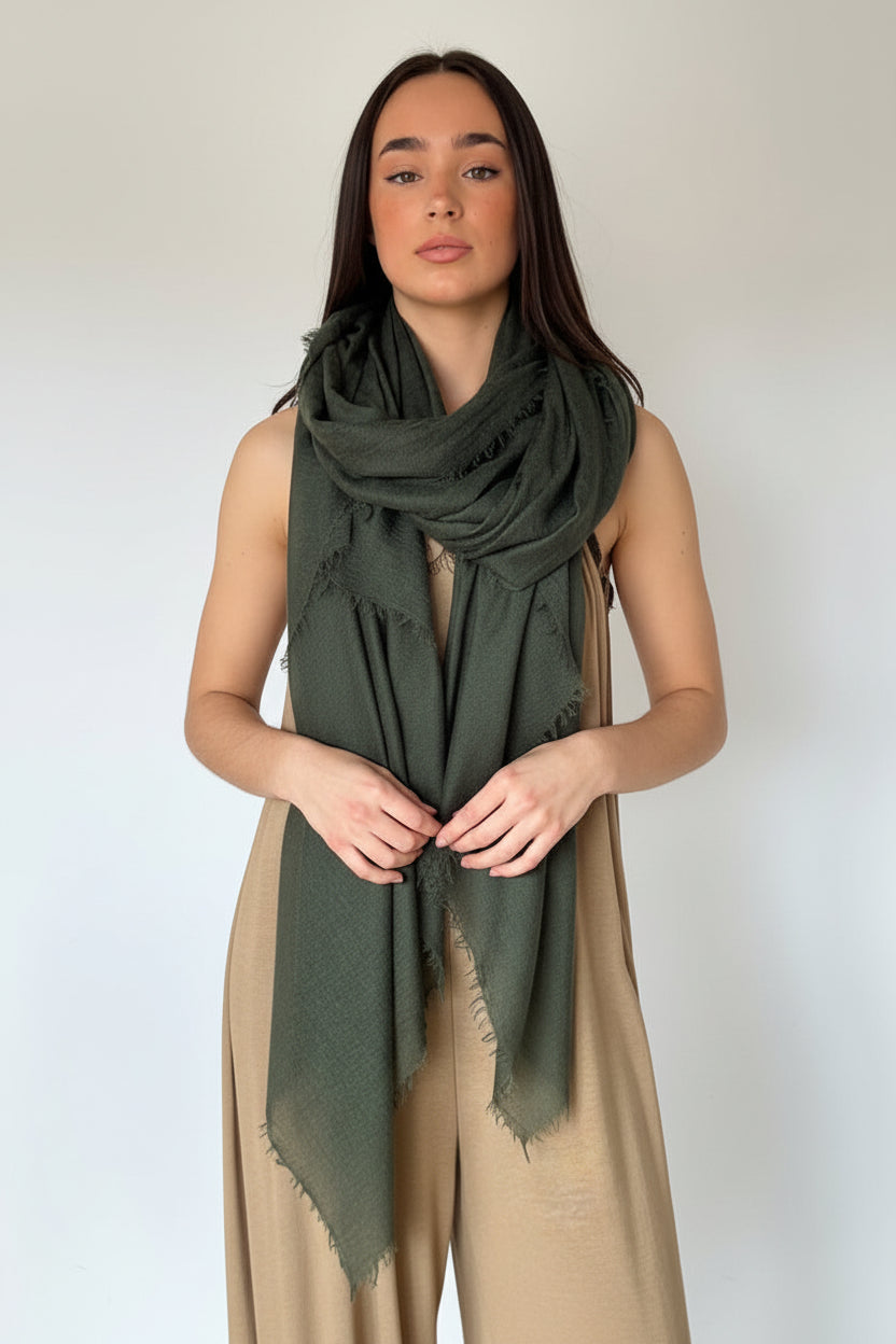 Woman wearing a green dress standing next to a beige curtain.