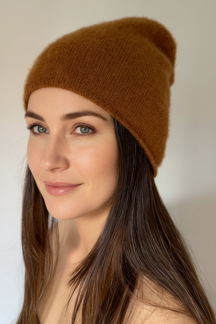 Woman wearing a  beety brown knit cashmere silkl beanie against a plain background