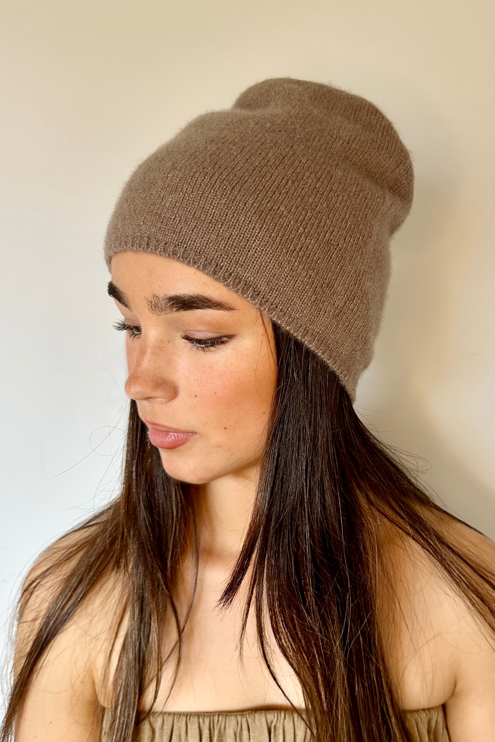 Woman wearing a  beety brown knit cashmere silkl beanie against a plain background
