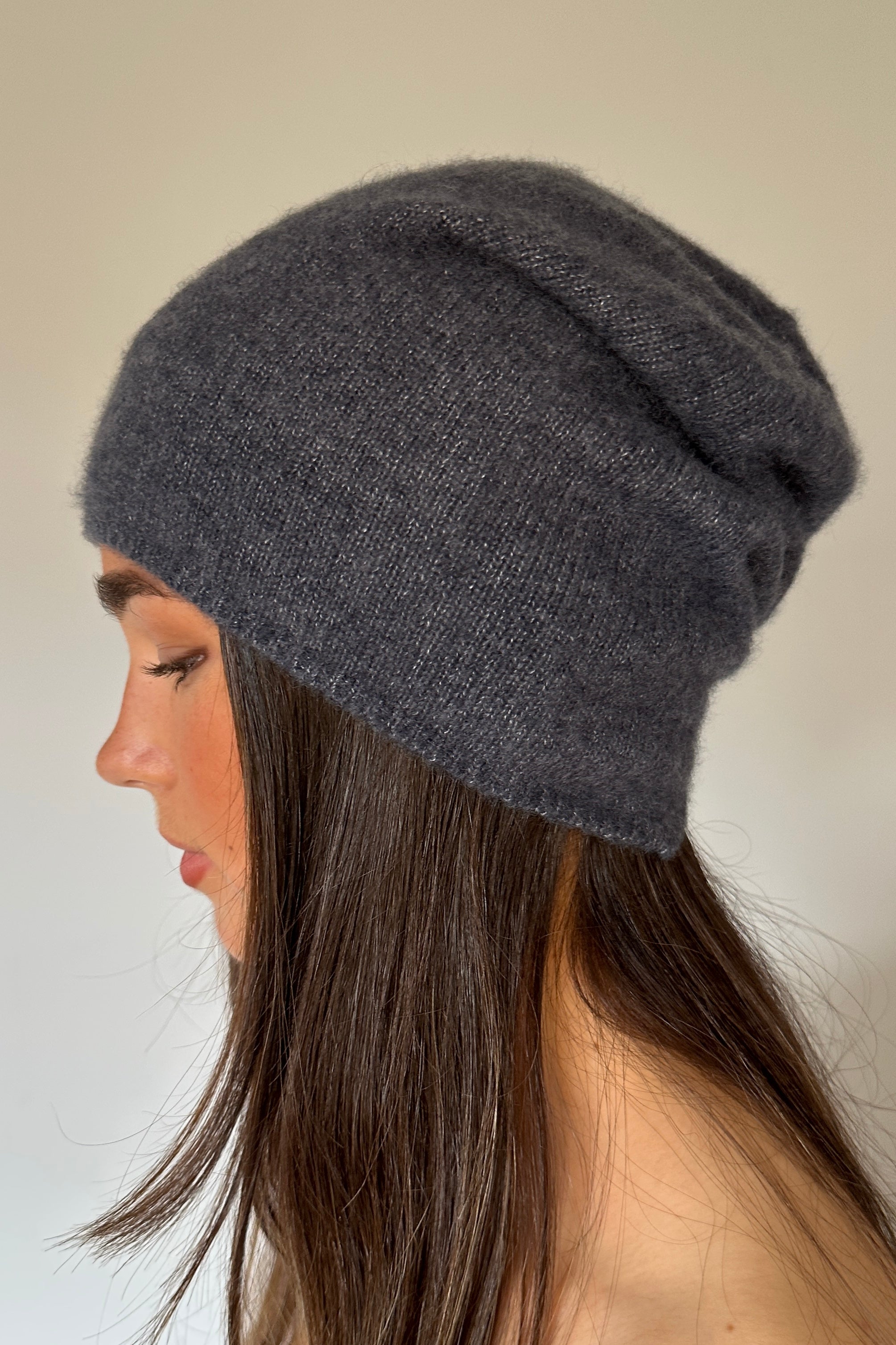 Woman wearing a indigo blue gray knit beanie against a neutral background