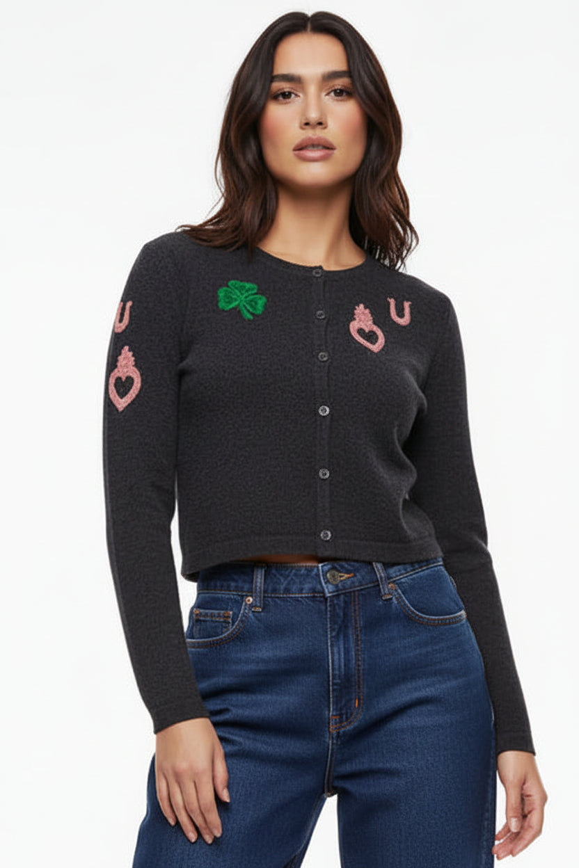 Woman wearing a grey cardigan with colorful designs on a white background