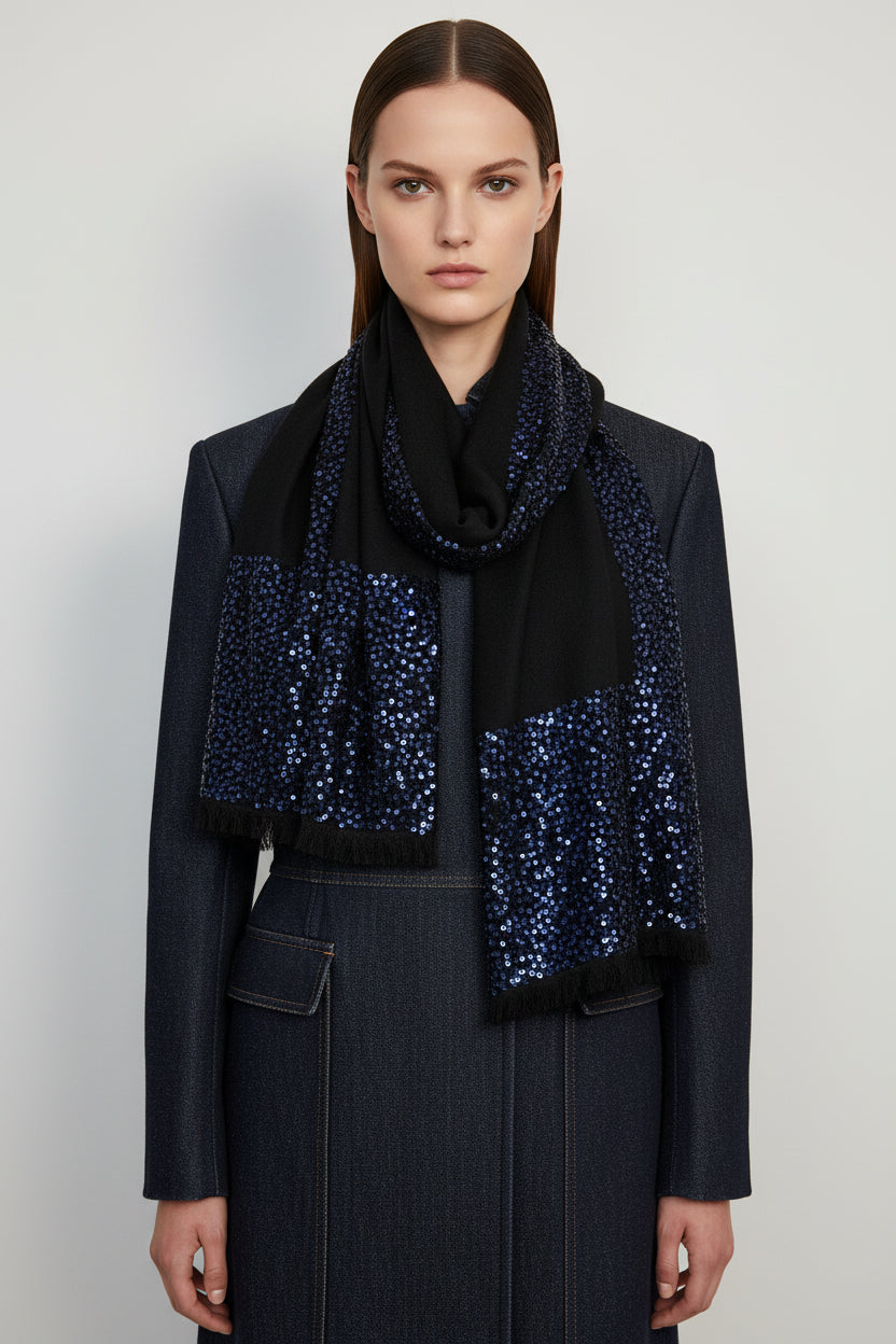 Woman wearing a black outfit with a blue sequin scarf on a plain background