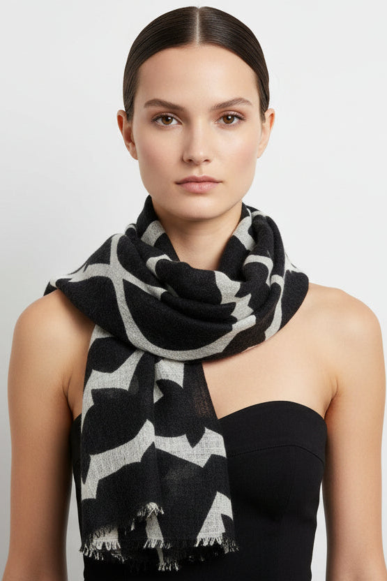 Woman wearing a black and white patterned scarf on a plain background