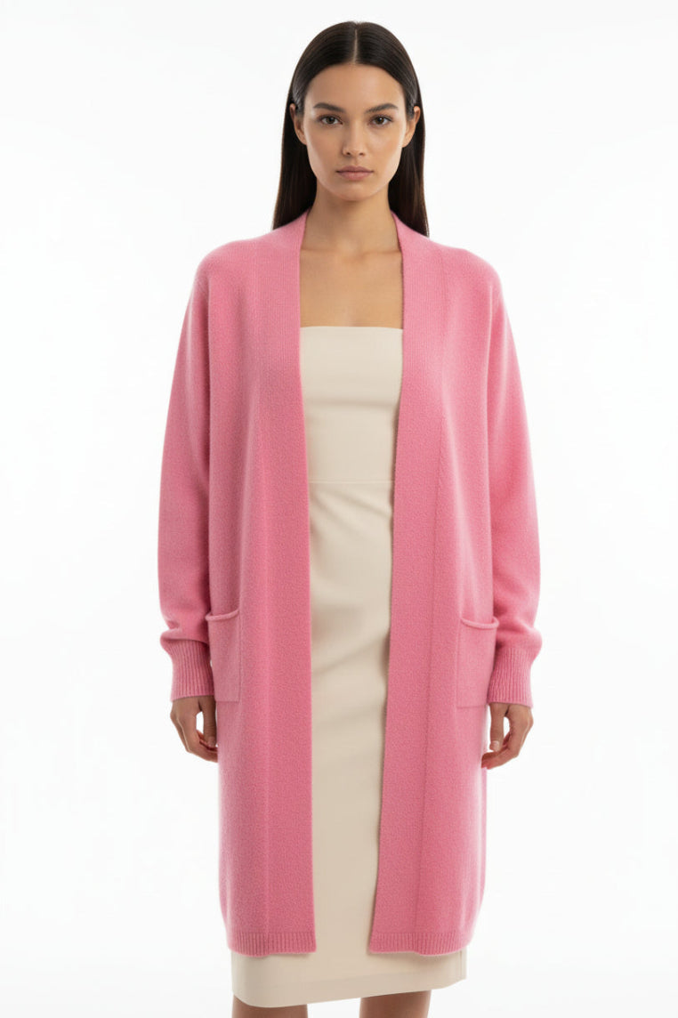 Model nwearing a long pink cardigan against a plain wall.