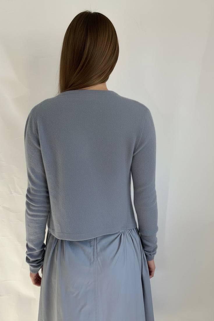 Person wearing a gray long-sleeve top and light gray pants on a white background