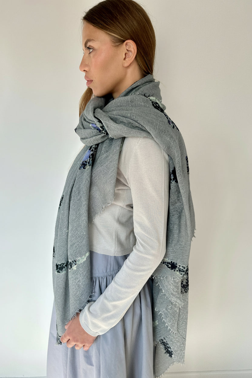 Woman wearing a gray scarf with black floral patterns against a white background