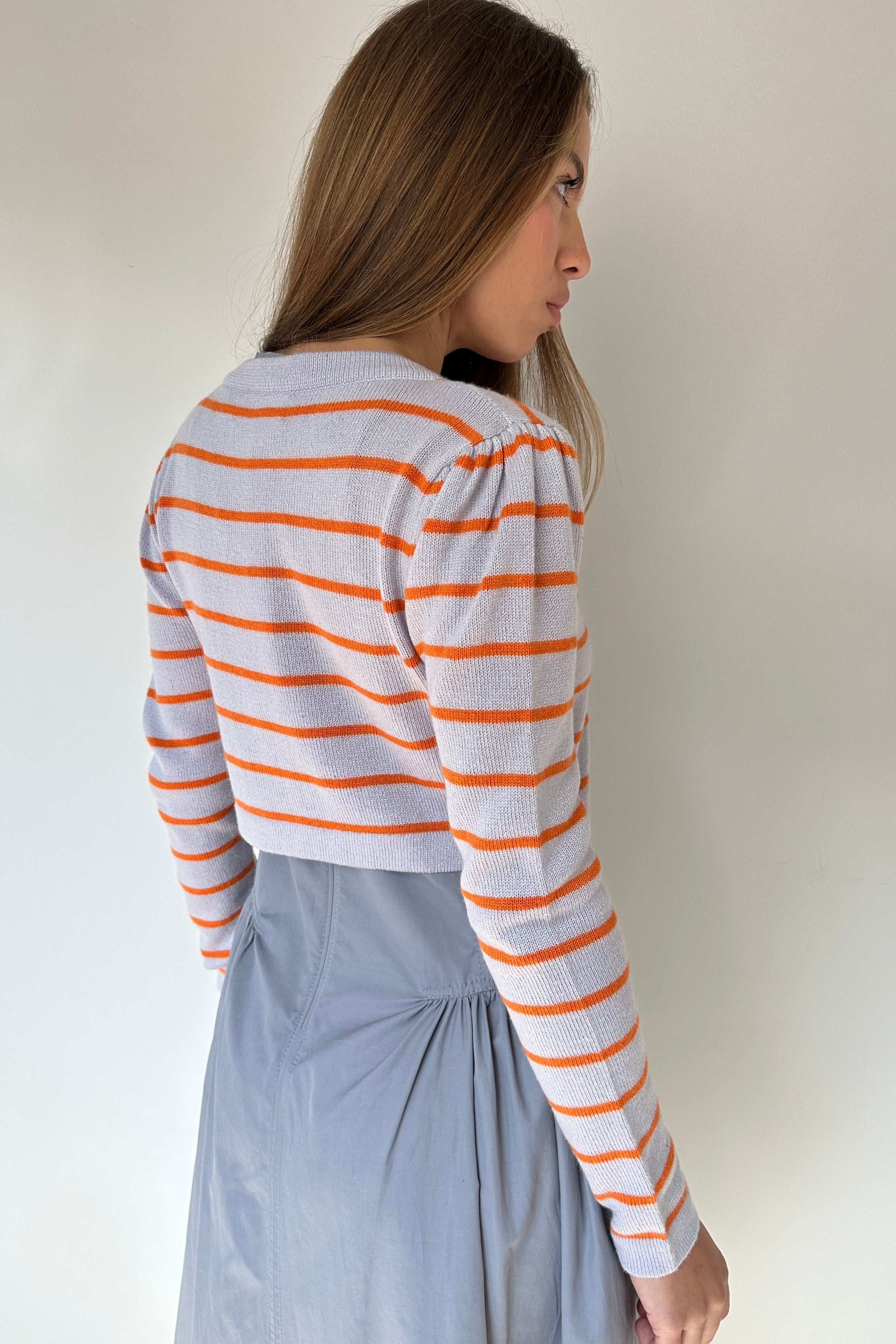 Person wearing a striped shirt and blue pants on a white background