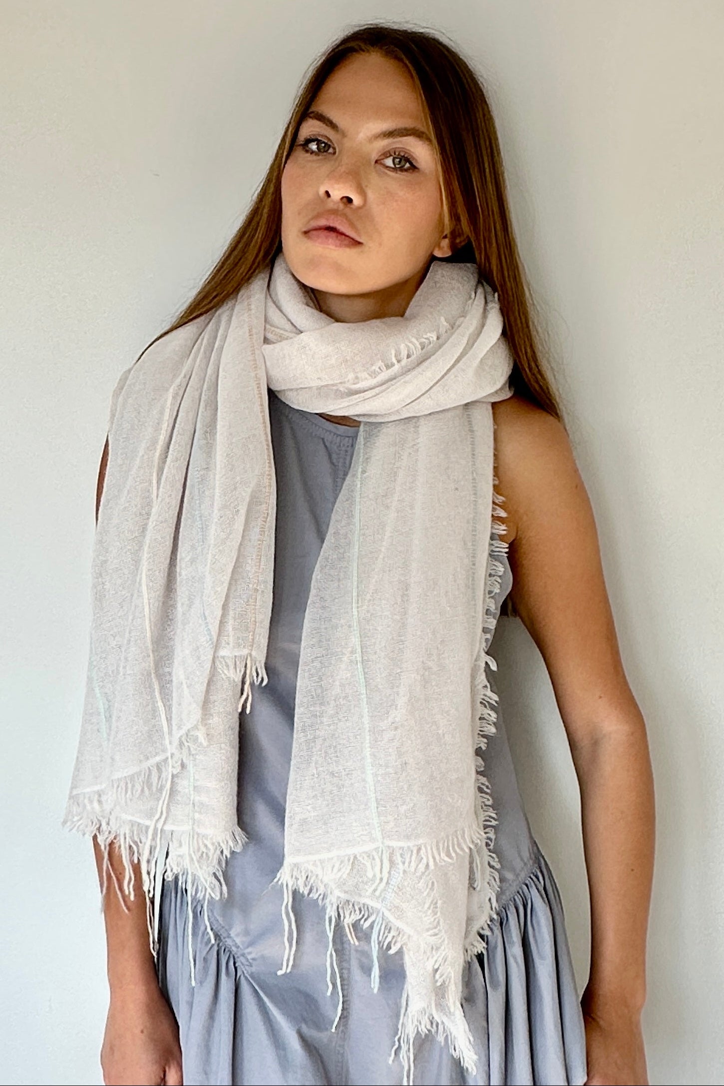 Woman wearing a light gray scarf against a plain background