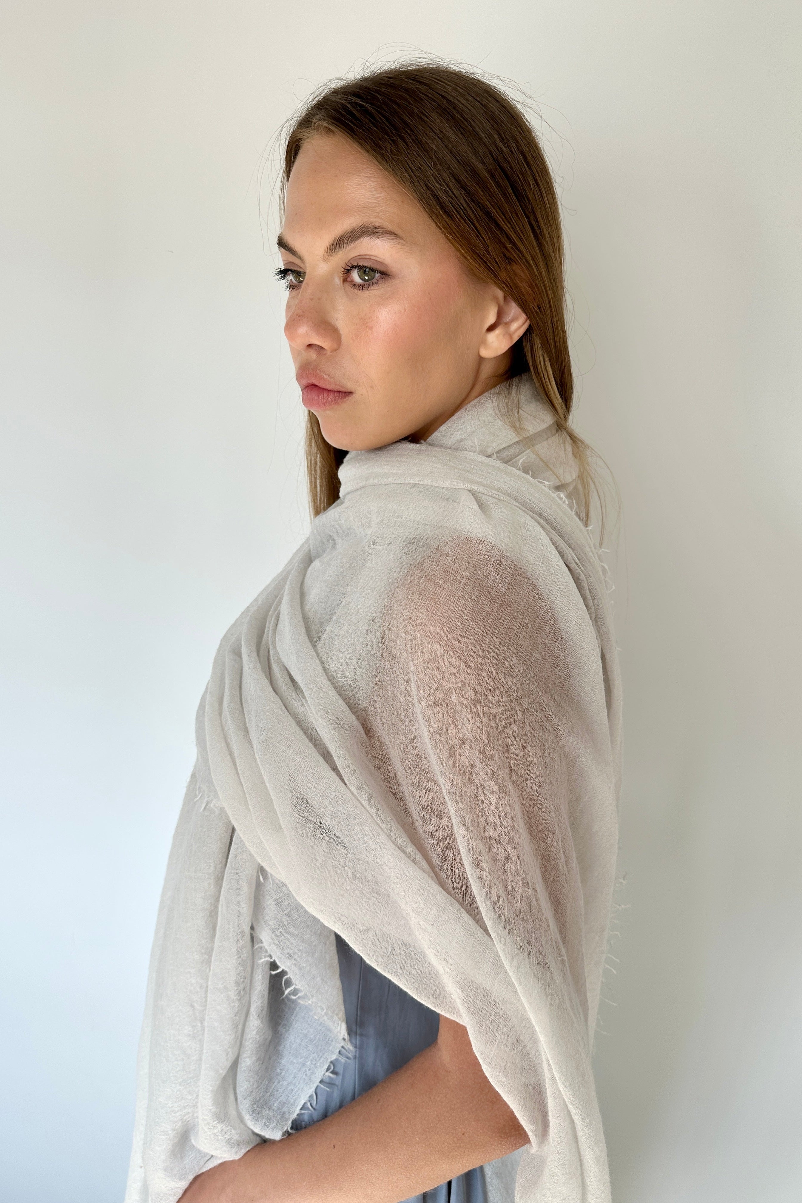Woman wearing a light gray scarf against a white background