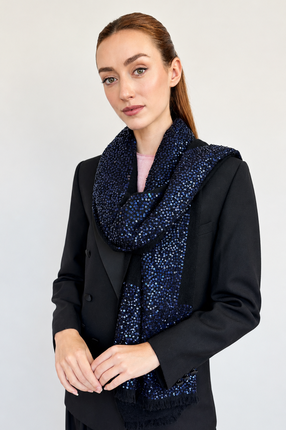 A woman wearing a black blazer and skirt, styled with a black cashmere with dark navy blue sequins featuring a sparkling, textured pattern.